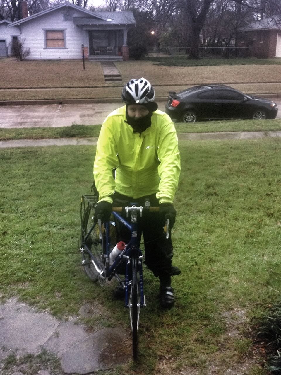 Color photo of myself in rain gear coming home with my bike in a rain storm.
