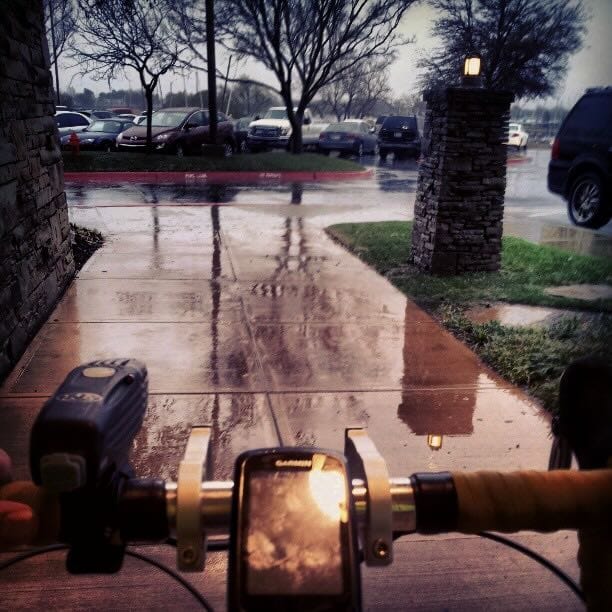 Color photo looking out over my handlbars out into a rainy parking lot.