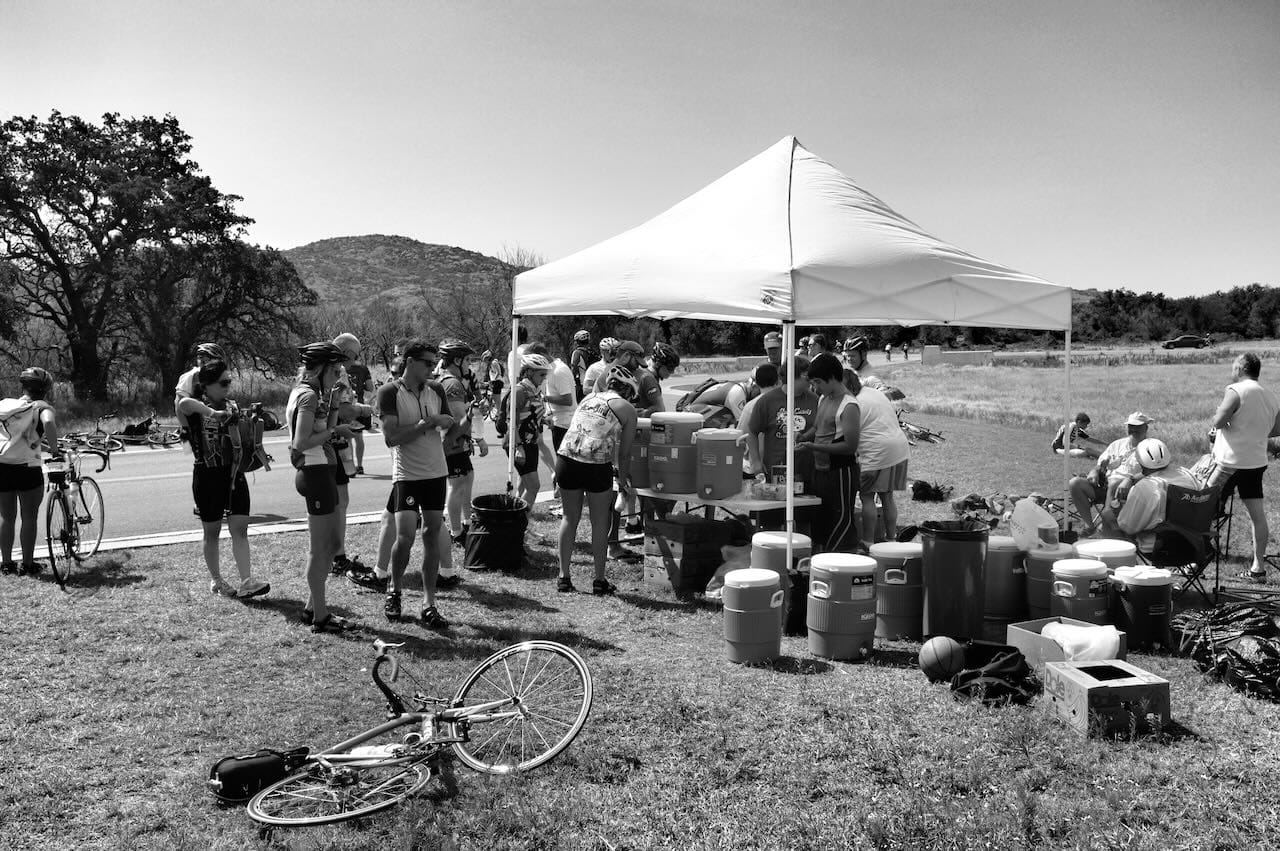 B&W photo of cyclists stopped at a rest stop.