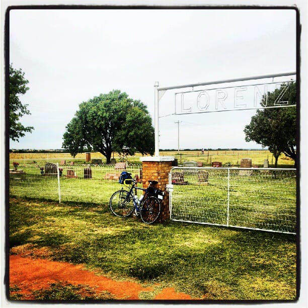 Color photo a bicycle leaning against the entrance to a cemetary with the Lorenz name on top of it.